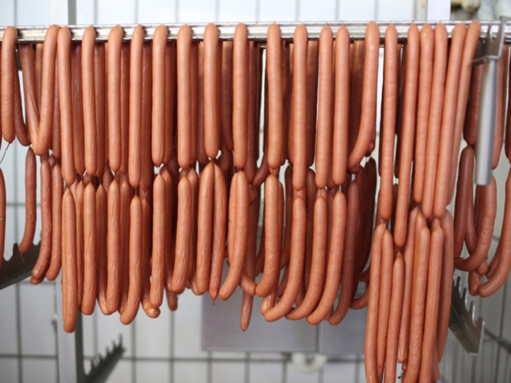 Frisch hergestellte W&uuml;rstchen h&auml;ngen zur weiteren Verarbeitung in der Fleischerei