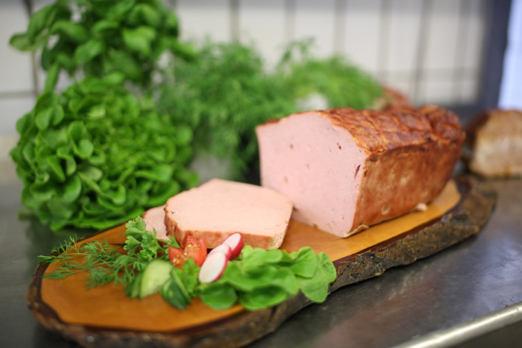 Fleischwurst aus eigener Herstellung Aufgeschnittene Fleischwurst mit frischem Salat und Kräutern