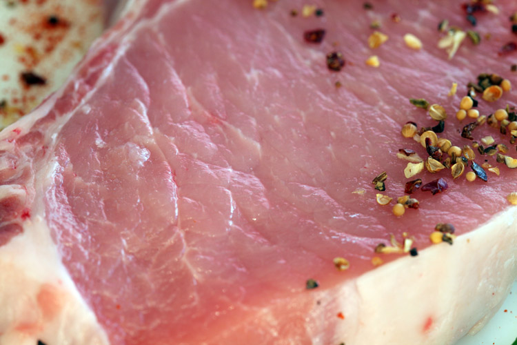 Frisches Fleisch mit Gewürzen Nahaufnahme eines frischen Fleischstücks mit groben Gewürzen